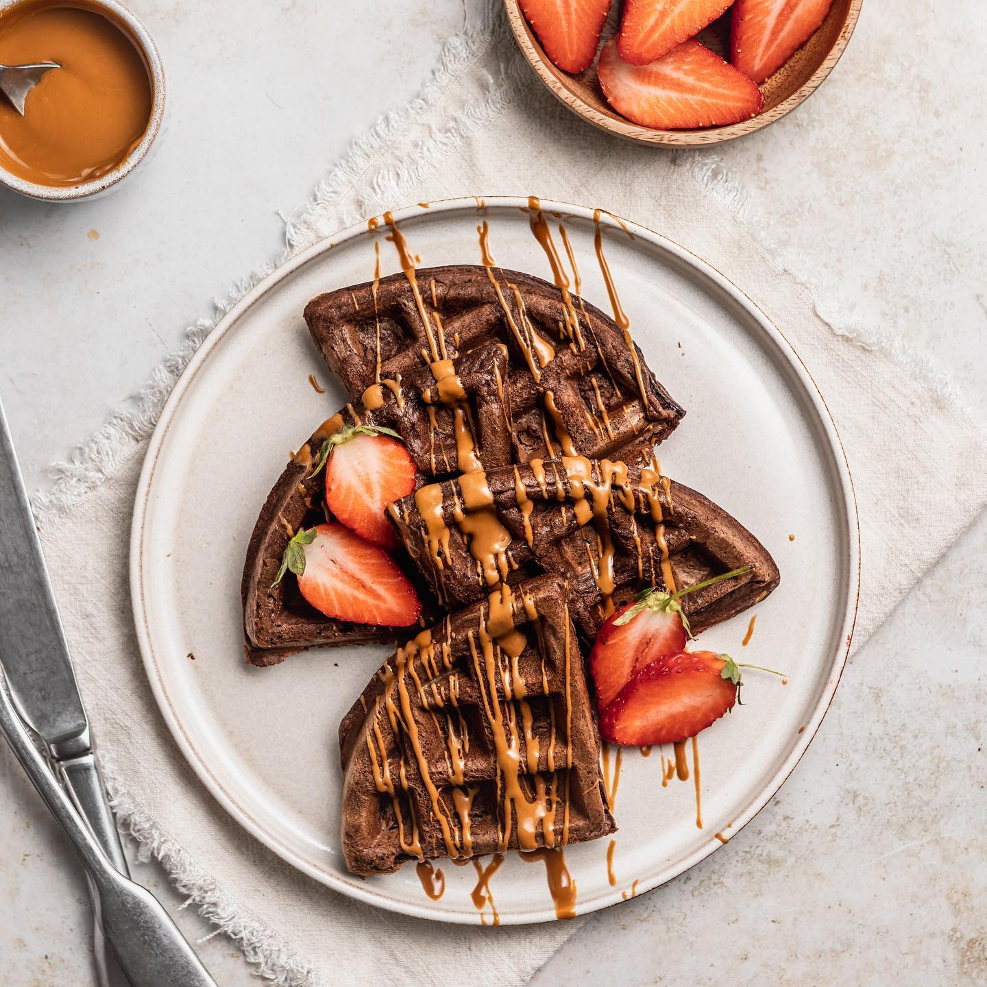 CHOCOLATE & BISCOFF PROTEIN WAFFLES//
I’m staying inside and eating waffles today- who’s with me!? 😂 The British weather certainly is confused right now 🌧 it feels like winter 😫. If you want to treat yourself to a tasty but quick and easy breakkie this morning hit SAVE to give this waffle recipe a try!

Serves 2
INGREDIENTS
50g self raising flour 
2 tbsp cocoa powder
25g chocolate protein powder
1/2 tsp bicarbonate soda 
1 tbsp maple syrup
1 large egg
120ml unsweetened almond milk
TOPPINGS
40g Biscoff spread, melted
80g sliced strawberries

METHOD
1. Make sure the waffle maker is preheated and lightly greased.
2. Add all the waffle ingredients together and whisk until smooth and combined.
3. Slowly pour half the batter into the waffle maker and close the lid. Cook for around 5 minutes until risen and fluffy.
4. Melt the Biscoff spread gently in the microwave, then drizzle over the top and add the sliced strawberries.

Per serving: Kcal 441 Carbs 46 Fat 18 Protein 23

Don’t forget to tag @sarahshealthykitchen if you give this one a try! 🤍